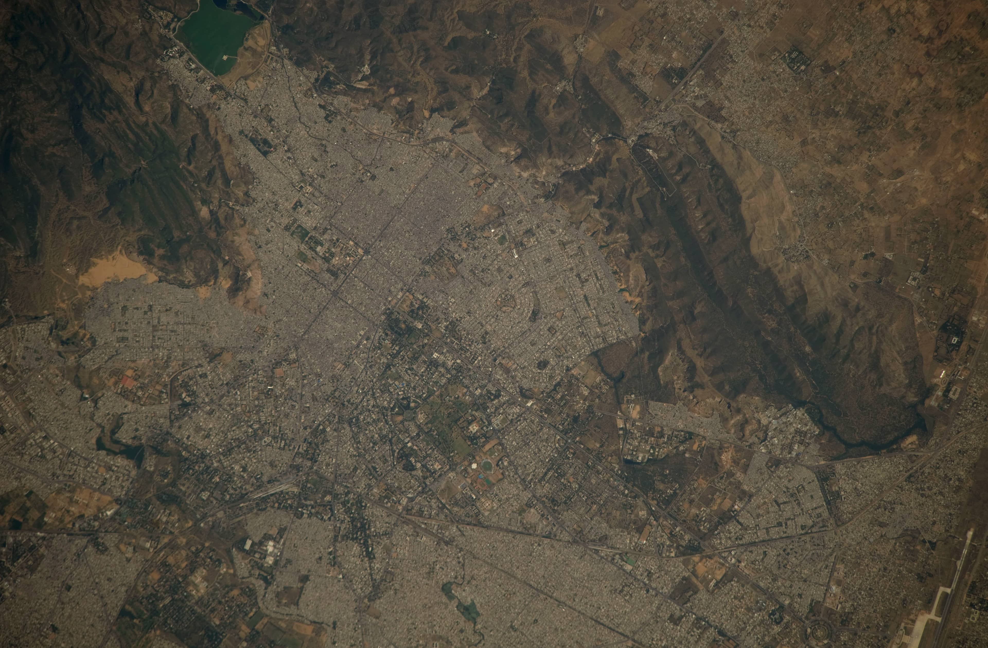 Jaipur photographed from the International Space Station: the dense city grid, Man Sagar Lake at the top left, and the Aravalli hills curving around the city.